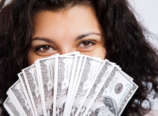 Woman holding a fan of hundred dollar bills in front of her face